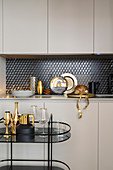 Serving trolley in front of fitted kitchen with glamorous golden accessories