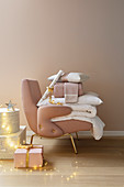 Geschenke, Decken und Kissen auf rosafarbenem Sessel