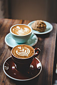 Cappuccino in bunten Tassen und Cookie