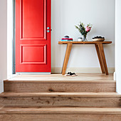 Steps leading to console table in hallway and open red front door
