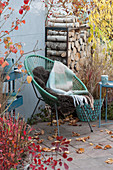 Acapulco armchair with blanket and fur on the terrace with Chinese reeds, red grass, wig bush and firewood