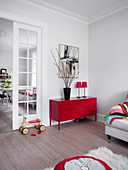 Red metal sideboard and ride-on toy in living room