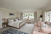 Double bed, sofa and dressing table in bright bedroom with bay window