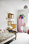 Bett, Wandregale aus alten Kisten und rosa Kleiderschrank im Mädchenzimmer