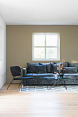 Graues Polstersofa, Stuhl und Couchtisch im Wohnzimmer mit olvigrüner Wand