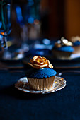 Perfectly decorated cupcake with blue icing and gold rose