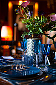 Blue glasses and plates and vase of flowers on festively set table