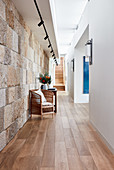 Wicker armchair in large hallway with stone wall and wooden floor