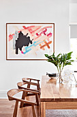 Abstract painting above modern wooden dining table