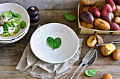 A spinach-leaf heart on a plate next to spinach gnocchi and raw potatoes