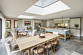 Country-house kitchen and dining table below skylight in spacious open-plan interior