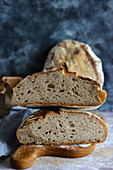 A halved loaf of sourdough bread on a wooden board