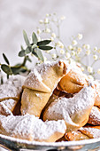 Brittle croissants on a plate sprinkled with powdered sugar