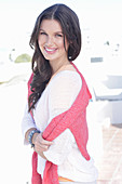 A young woman wearing a white summer jumper and a fuchsia-coloured jumper over her shoulders