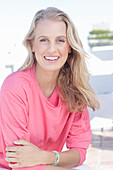 A young blonde woman wearing a pink blouse with gigot sleeves