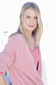 A young blonde woman wearing a pink wrap-around jumper