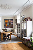 Two glass-fronted cabinets in dining room with stucco ceiling and wooden floor