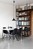 Black shell chairs at dining table and bookcase against brick wall