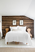 Rustic wooden wall behind bed in country-house bedroom