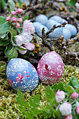 Artistically painted wooden Easter eggs next to apple blossom