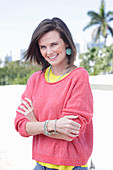 A young woman wearing large earrings, a fuchsia jumper and a yellow top