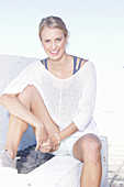 A young blonde woman wearing a white summer jumper