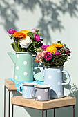 Gerbera daisies, ranunculus and anemones in pastel jugs with polka-dot patterns