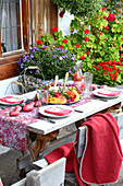 Gedeckter Tisch mit bunten Kartoffeln und Blumenkranz