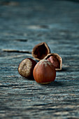 A whole and an open hazelnut on a wooden surface