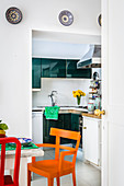 Esstisch mit farbenfrohen Stühlen neben Durchgang zur Küche