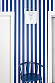 Dark blue chair against blue-and-white striped wallpaper