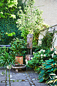 Terrassen-Dekoration mit Kunstobjekt, Kübelpflanzen und Wasserschale