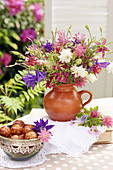 Bouquet of mixed aquilegias and bowl of pastries on terrace table