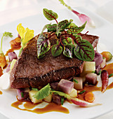 Broiled Flap Steak on a bed of root vegetables and demi glaze with red veined sorrel garnish