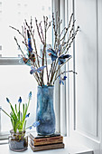 Flowers and branches of pussy willow decorated with paper butterflies on windowsill