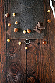 Wooden cutting board on table with hazelnuts and chocolate