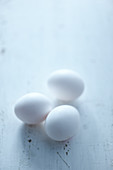 Three white chicken eggs on a light background