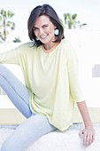 Junge Frau in apricotfarbenem Top, gelbem Pulli und Jeans