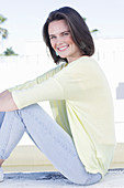 Junge Frau in apricotfarbenem Top, gelbem Pulli und Jeans