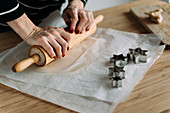 Woman rolling dough on table in kitchen