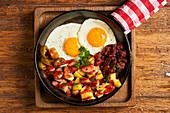 Fried eggs with vegetables in pan