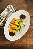 Fried cheese sticks with sliced cucumber and barbecue sauce on plate on wooden table