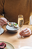 Person with glasses of champagne trying oysters with lemon and herbs in restaurant