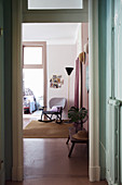 View from hallway into pink interior with vintage rocking chair and standard lamp