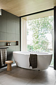 Floating, free-standing bathtub next to glass wall