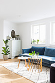 Delicate coffee table and three-legged table in front of blue sofa