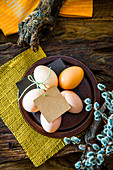 Frische Eier und ein gefärbtes Ei auf österlich dekoriertem Tisch