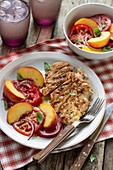Grilled chicken breast with salad made of tomatoes, peaches, with red onion and basil