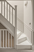 White staircase with white wooden banister and white wainscoting