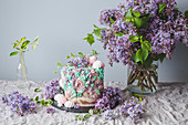 Festtagstorte dekoriert mit Baiser und violetten Fliederblüten